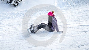 Girl snowboarder fell and sitting on the snow