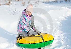 Girl with snowtube on snowy downhill