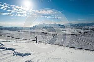Girl on the snowy slope with mountains and the sea on background.