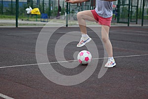 Girl soccer player with a pink soccer ball  on a soccer field or brown background