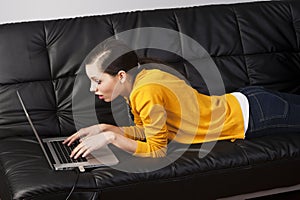 Girl on sofa with laptop, she indicates the displa