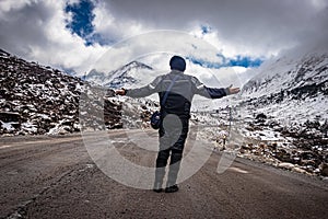 Girl solo traveler at isolated tarmac road with snow cap mountains in background at morning