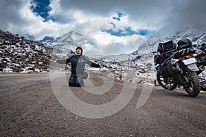 Girl solo traveler at isolated tarmac road with snow cap mountains in background at morning