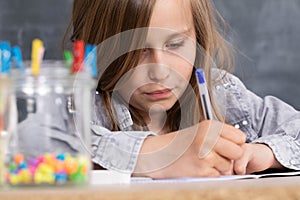 The girl solves the task given in the classroom. The schoolgirl diligently writes in a notebook