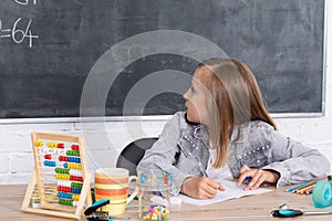 The girl solves the task given in the classroom. The schoolgirl diligently writes in a notebook