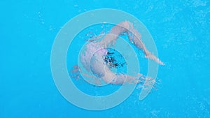 Girl somersaults and plays in the transparent blue swimming pool water. Child have fun in swim pool. Full HD slow motion