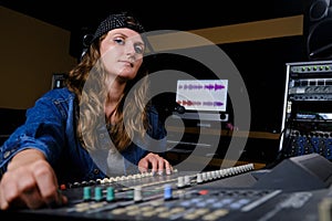 Girl sound engineer controls the mixing console. Professional recording of singers in the Studio. Young woman at the controls in