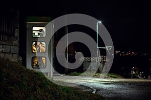 girl speaks in the night telephone booth. mystical and mysterious street phone