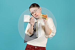 Girl speaks on the phone, holds documents under the armpit and eats a sandwich