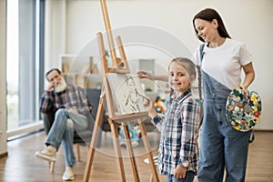 Girl spending time with mom and grandpa in art studio