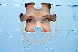 The girl spies through a blue puzzle photo