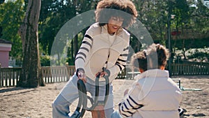 Girl spinning carousel mother at modern playground closeup. Family enjoy leisure