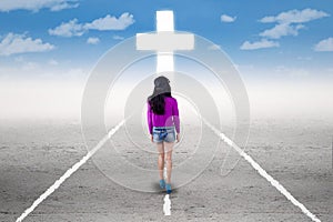 Girl in a spiritual journey with a cross