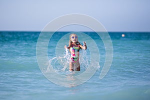 The girl splashes and plays at sea.