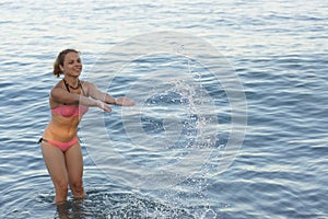 The girl splashes in the sea water.