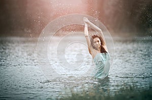Girl splashing water in lake by her hands. Motion