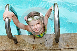 Girl in sport goggles leaves pool.