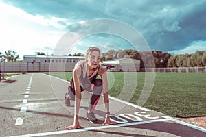 Girl on sports circle, summer city on sports ground, stands before start of race, training distance running, active