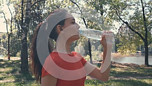 A girl after sports, drinking water on the street. Outdoor fitness.