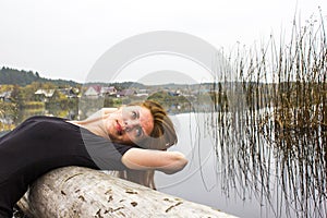 Girl with sports figure on background of calm autumn river. Yoga, Meditation, Relax