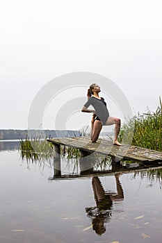 Girl with sports figure on background of calm autumn river. Yoga, Meditation, Relax