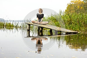 Girl with sports figure on background of calm autumn river. Yoga, Meditation, Relax