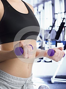 Girl in sports suit with beautiful purple fitness dumbbells.