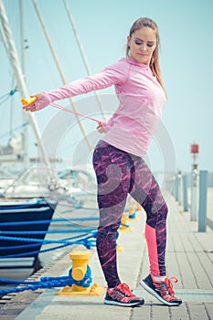 Girl in sports wear exercising with jumping rope in seaport, healthy active lifestyle