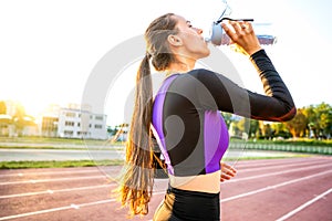 girl sportsman crossfit and squats agains and drinks water at sunset