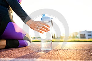 girl sportsman crossfit and squats agains at sunset in the stadium drink water