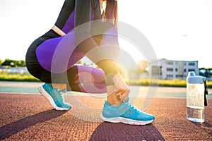 Girl sportsman crossfit and squats agains tying shoelaces and st