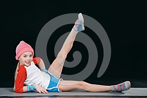 Girl in sportswear exercising isolated on black