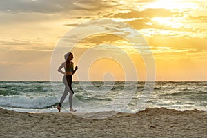 Girl in sportswear running along the surf line. Early morning