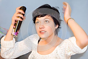 Girl spraying hair lacquer onto her hair photo