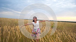 Girl spread her arms like wings and walks across field smiling. Slow motion.