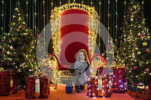 girl squats among gift boxes, festoons,