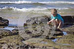 Girl Squatting on Rocks at Sea