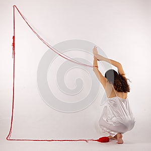 Girl squatting white silk nightie making frame with red thread on white background