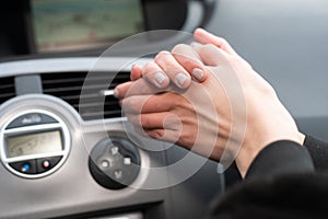 The girl squeezes her hands and warms them over the hot air outlet in the car. Cold hands.