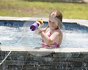 Girl squirting water from a swimming pool