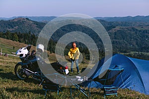 A girl stand alone on the top of the mountain. Back view. adventure motorcycle, camping tent, enduro active extreme trip