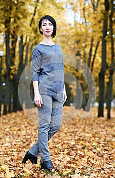 Girl stand in autumn park with yellow trees, fall season