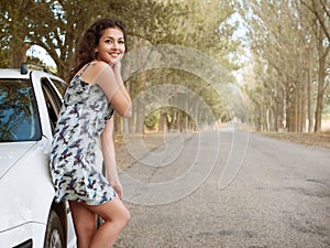 Girl stand on country road near car, big high trees, summer season