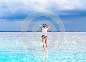 A girl stand on the surface of a salt lake at a spa resort. Young woman on the beach with white sand admires beautiful