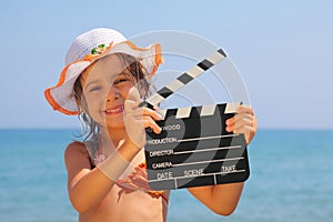 Girl standing on beach and holding clapboard photo