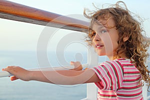 Girl standing on cruise liner deck, hands on rail