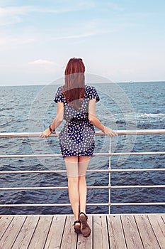 Girl standing on the dock watching the sea ocean