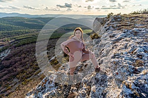 The girl is standing on the edge of the cliff and looking at the sun valley.Woman enjoying a sunset or sunrise from the