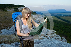 Girl standing at the edge of mountain and looking at map