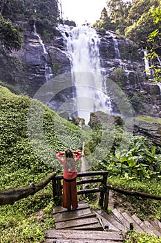 Girl standing in forest near huge waterfall in jungle of thailand